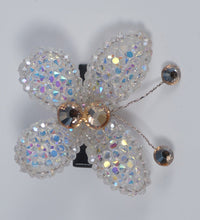 Butterfly-shaped brooch with rhinestone embellishments on a light gray background