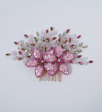 Decorative hair comb with pink flowers and gemstones on a white background
