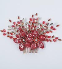 Decorative hair comb with red flowers and gold accents on a white background