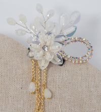 Decorative hairpiece with flowers, beads, and chains on a textured surface