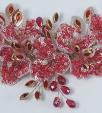 Decorative red floral embellishment with gold accents on a white background